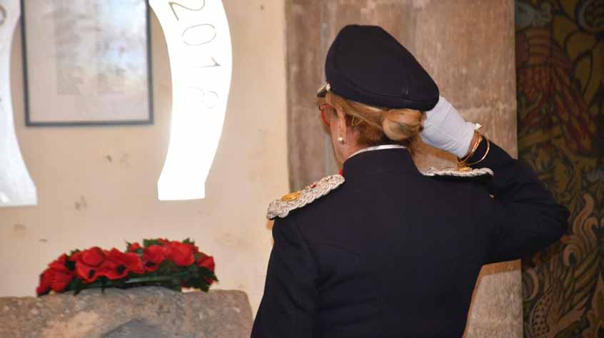 Person saluting to poppy wreath