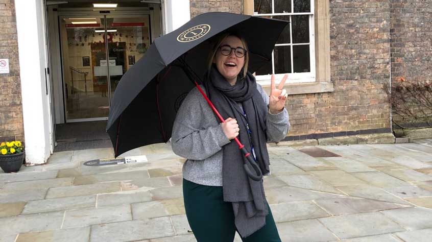 Person holding a centenary branded umbrella