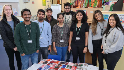 Diwali volunteers pose for a photo in a classroom with crafts around them.