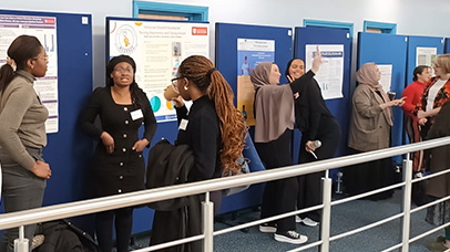 Students next to a display of posters at the MREM conference
