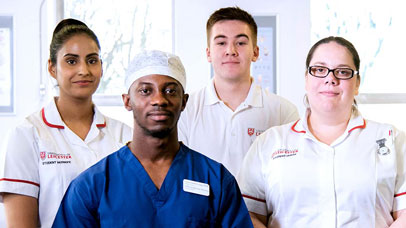 Four healthcare workers looking at the camera, dressed in scrubs and nurse's uniforms.