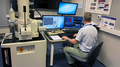 Researcher sitting working at the Jeol7200 Scanning Electron Microscope, with EDX, EBSD, STEM