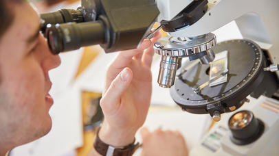 A man using an optical microscope. 