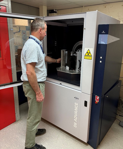 Researcher with the door open of the Bruker D8 getting samples ready for X-ray diffraction