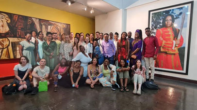 Students posing together for a picture surrounded by large works of art.