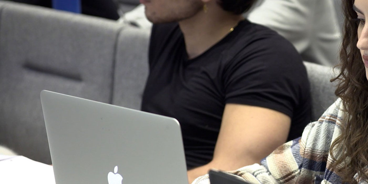 student working on laptop in a lecture theatre
