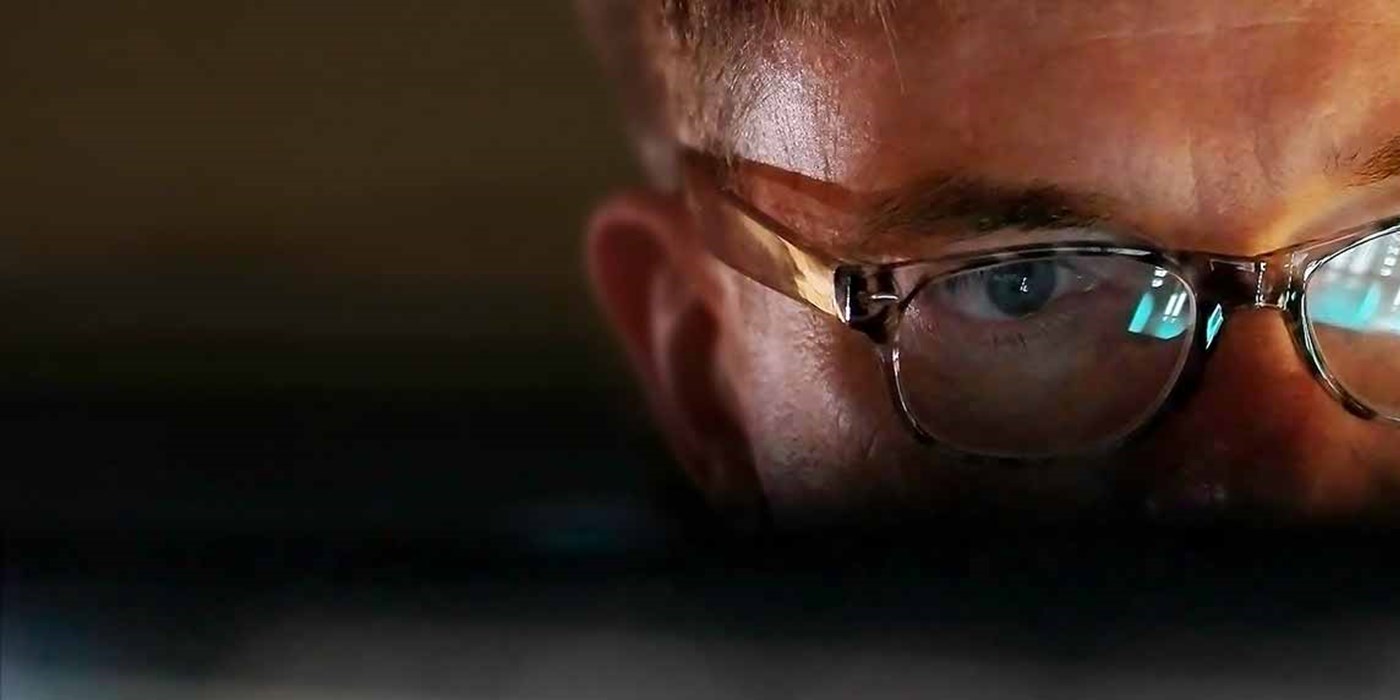 person using a computer with the screen reflected in their glasses