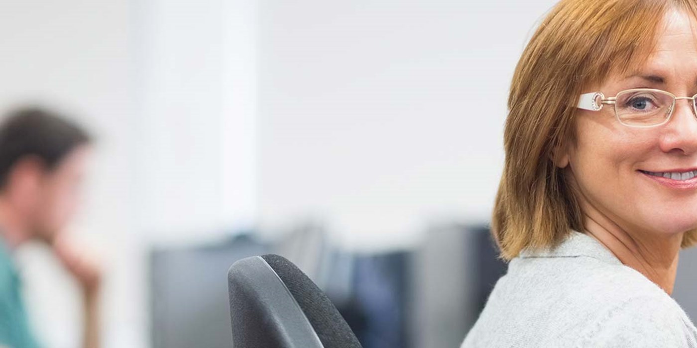 smiling woman by other mature students in the computer room