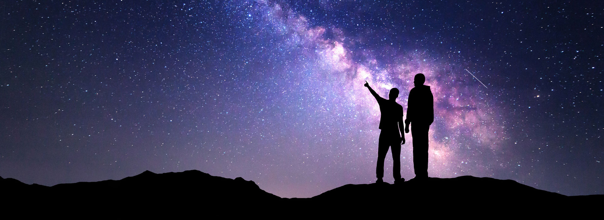 Milky Way with silhouette of a family on the mountain.