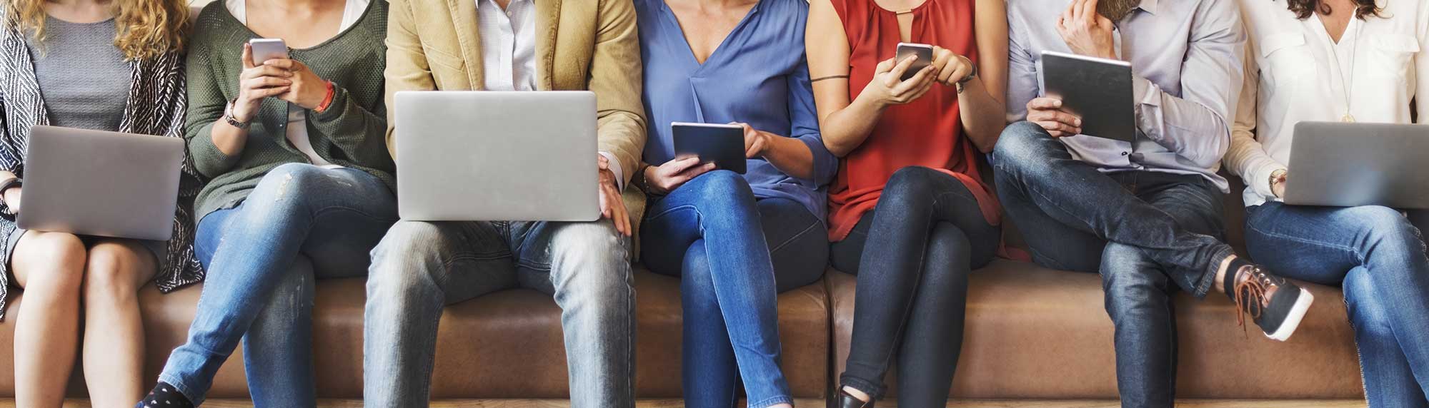 group of people sat using laptops phones and tablet computers