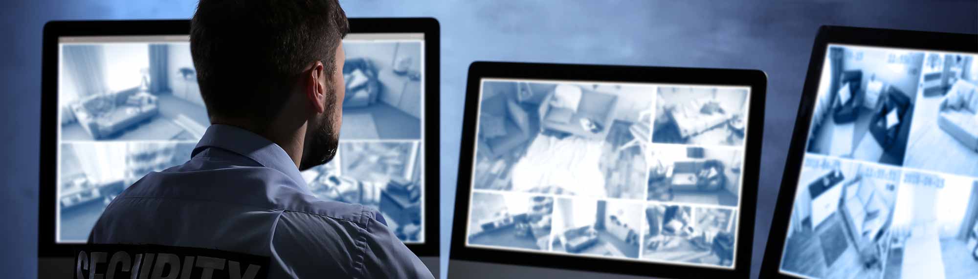 security guard watching banks of cctv footage