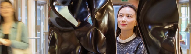 student inspecting a sculpture in the library entrance