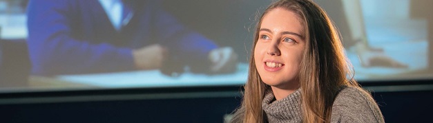 student sat in a film theater with a film showing on the background