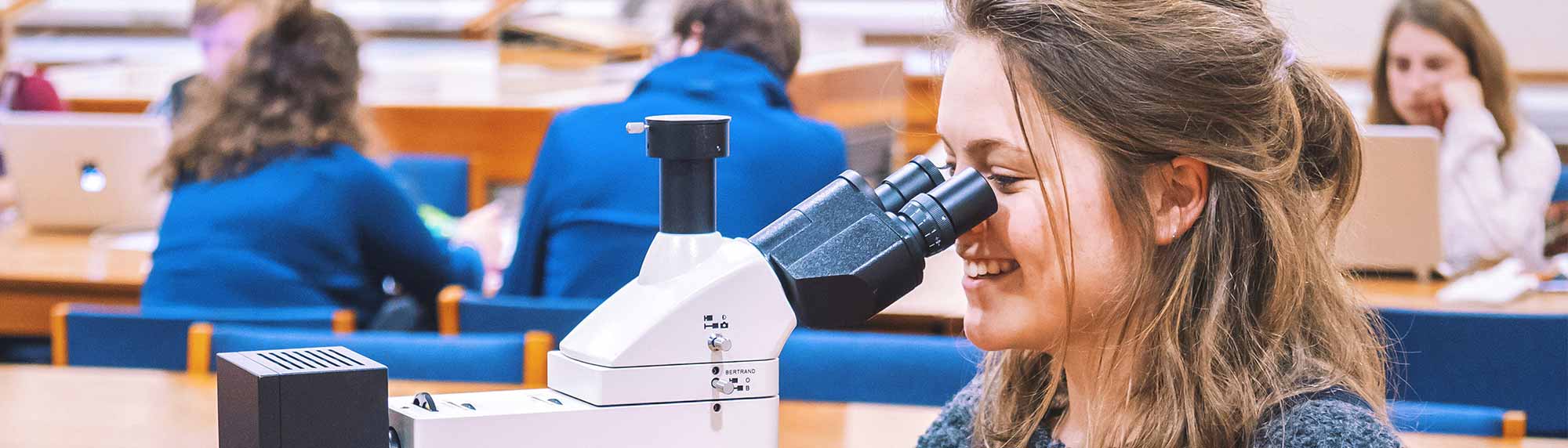 student using microscope in class