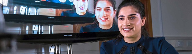 student with her image on a screen behind her
