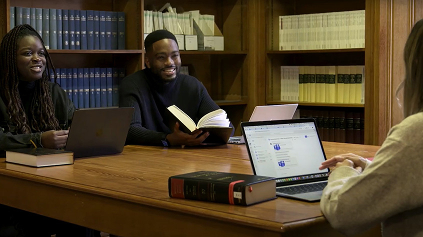 Two law students sat at a table with a third person who is using their latpop