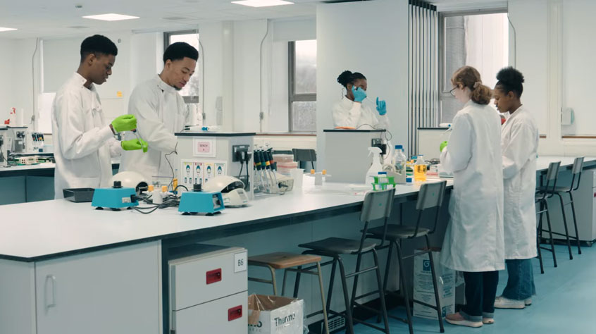 Students wearing lab coats and working in a lab.