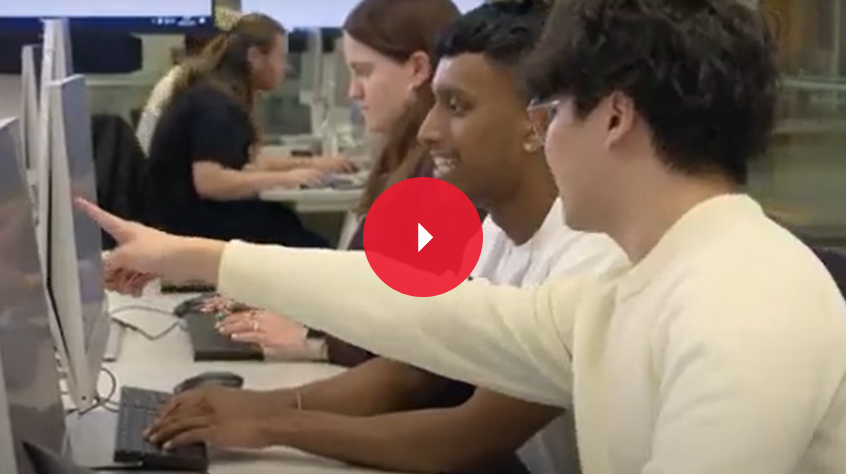 Three students on the computer. One points at the screen.