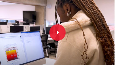 Student standing at a computer station in a computer lab