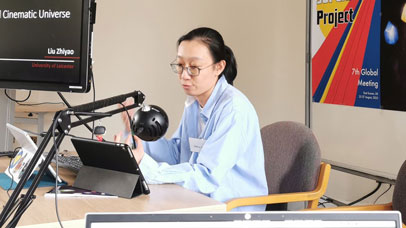 Woman sitting at a desk with a microphone and iPad in front of her.