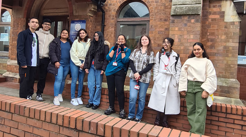 Groupe of people posing for a photo outside a school.