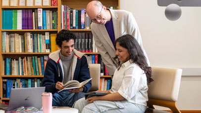 Students sitting in a lecturer's office, with the lecturer leaning over them