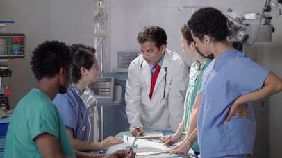 Doctor and students stood around a hospital bed.