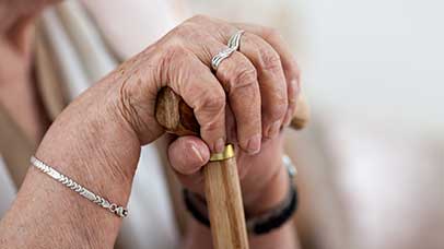 an elderly womens hand clutching a walking stick