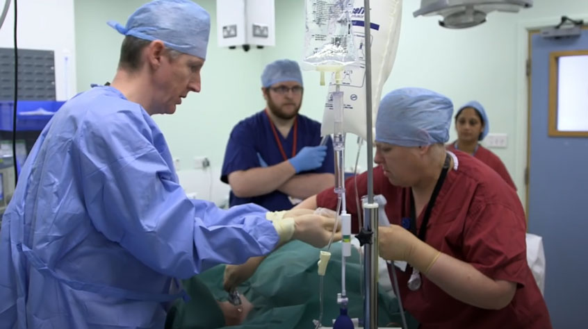 Surgeons in an operating theatre, gathered around a patient