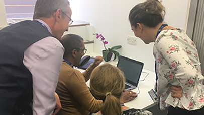 Photo: Leicester Clinical Trials team of 4 people looking at data on laptop screen
