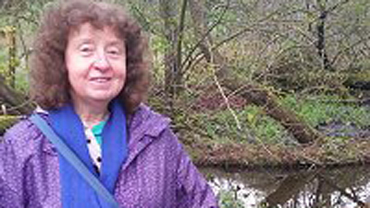 Angela Monckton standing in front of a lake.