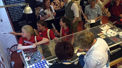 Group of people at the Richard III museum, examining artefacts in a cabinet.