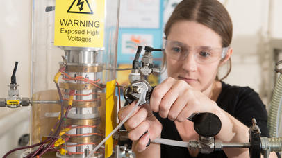 Woman using apparatus which has a warning sign of exposed high voltage 