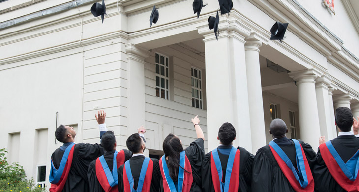 Graduates tossing hats in the air at De Montfort Hall
