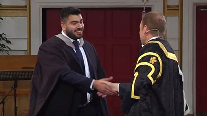 Student shaking vice chancellor's hand at graduation ceremony