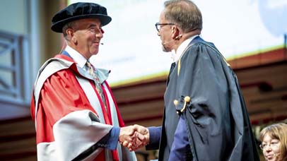 Two men in robes shaking hands on the stage