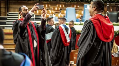 One Graduand taking a photo of another within De Montfort Hall