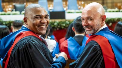 Two graduands smiling in De Montfort Hall