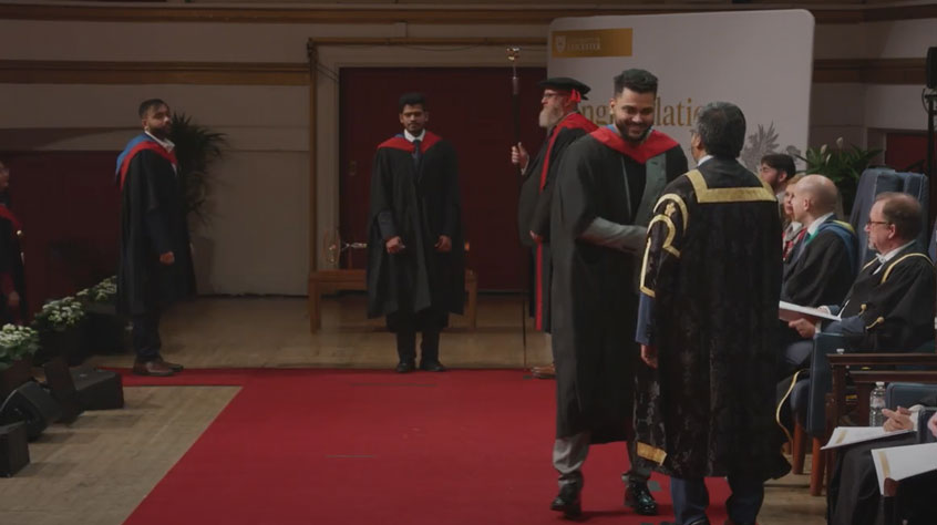 Graduates on the stage at De Montfort Hall, shaking the Vice-Chancellor's hand