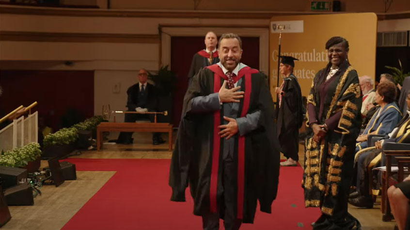 Graduate walking across a stage in graduation robes.