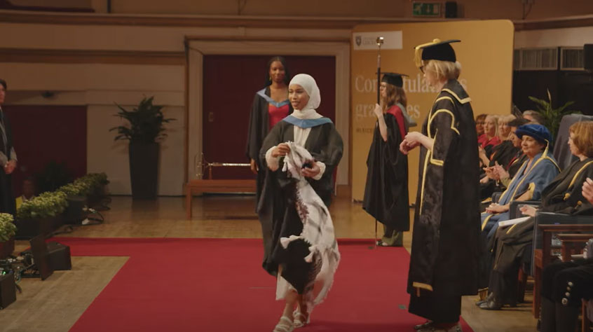 Graduate walking across the stage wearing graduation robes.