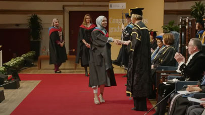 Student shaking hands with someone as they graduate.