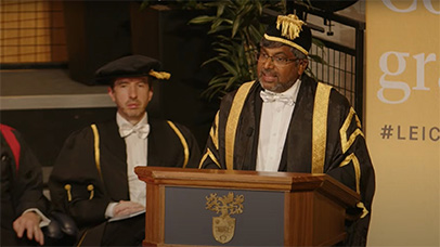 Professor Nishan Canagarajah speaking at graduation and wearing a cap and gown.