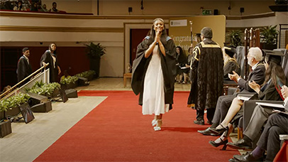 Student walking across the stage, smiling at the camera