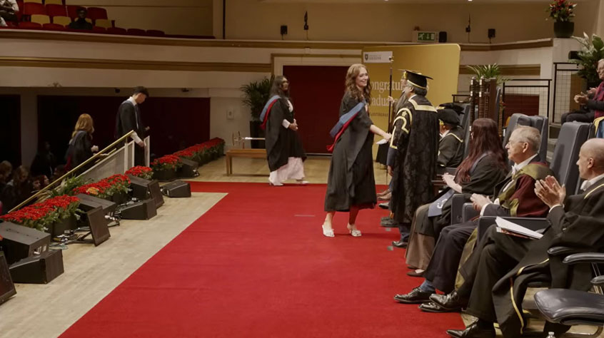 Students walking on to the red carpet and shaking hands at graduation.