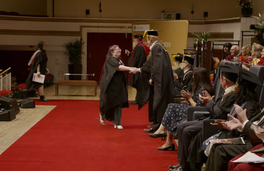 Graduate shaking hands with academic on stage