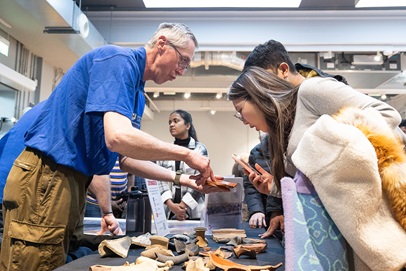 visitors examining archaeological items being shown to them at a stall