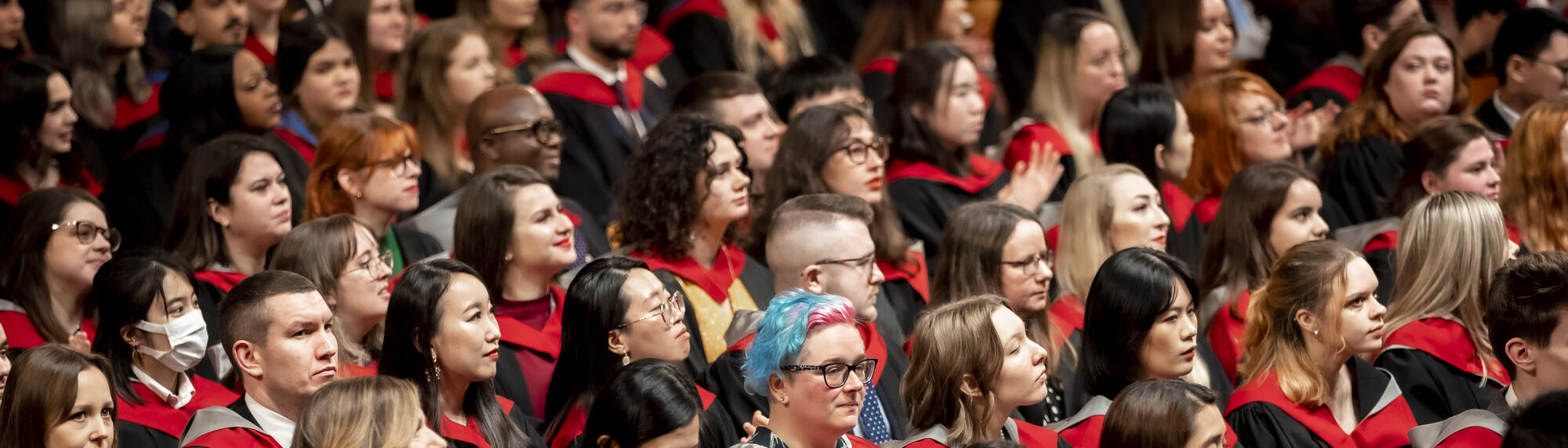 A crowd students seated in graduation gowns during a ceremony