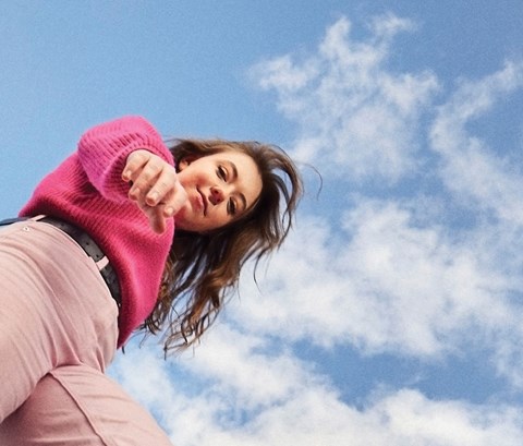 Student looking into the camera from up above with a bright blue sky behind her.