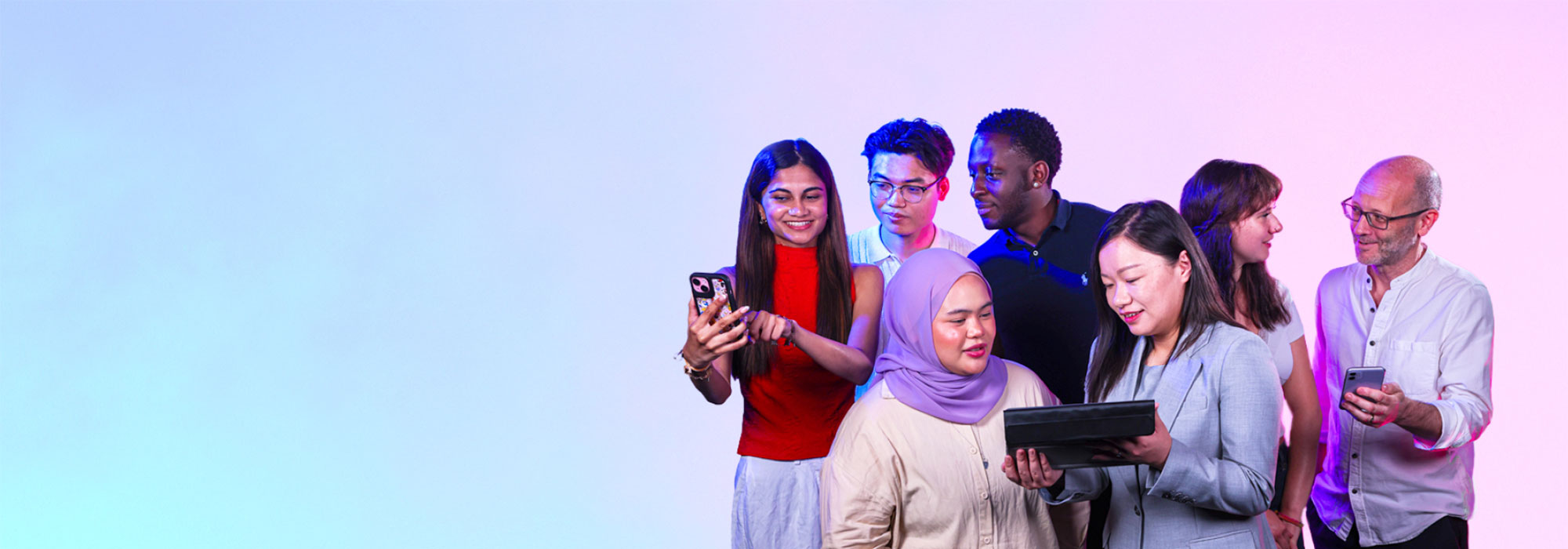 Image of seven people of mixed race and gender looking at a range of digital devices